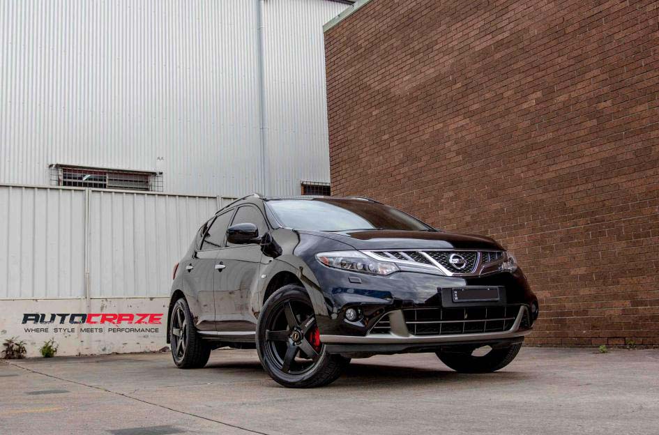 A black Nissan SUV parked in front of a brick wall, showcasing image.